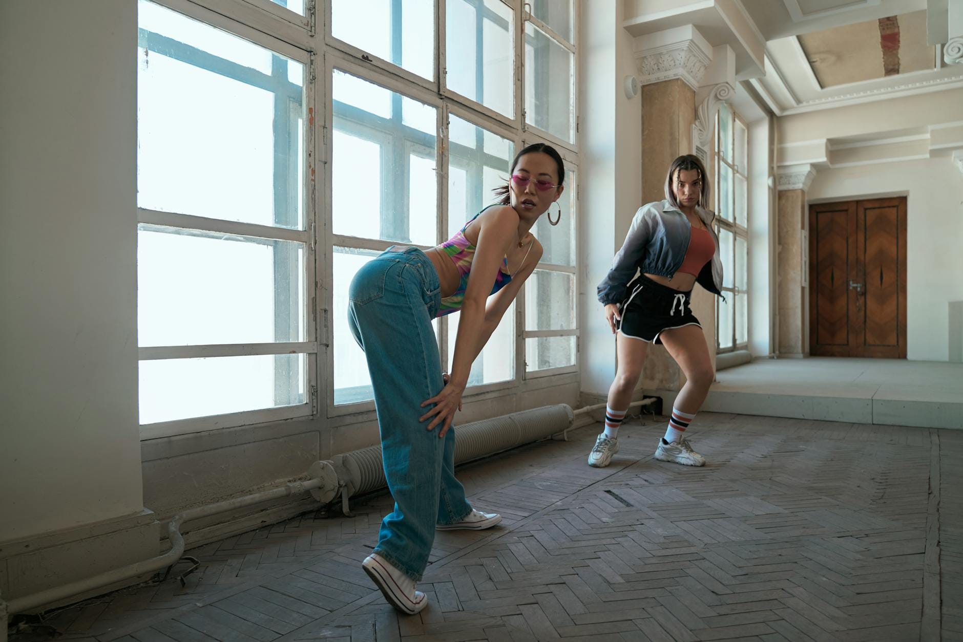 Dwie nastolatki ćwiczą energiczny taniec hip-hop w sali z drewnianą podłogą