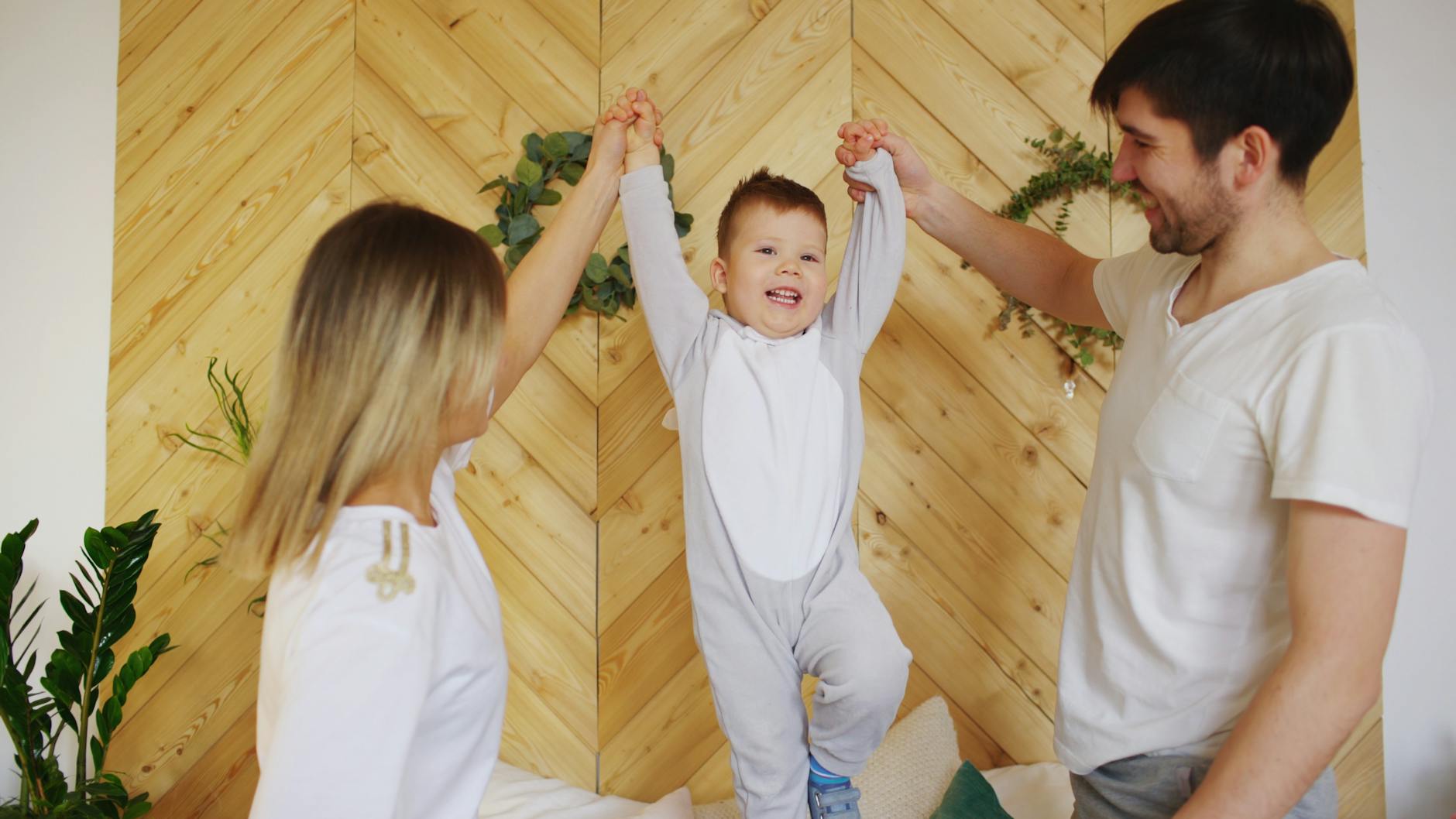 Uśmiechnięci rodzice unoszą dziecko w domu