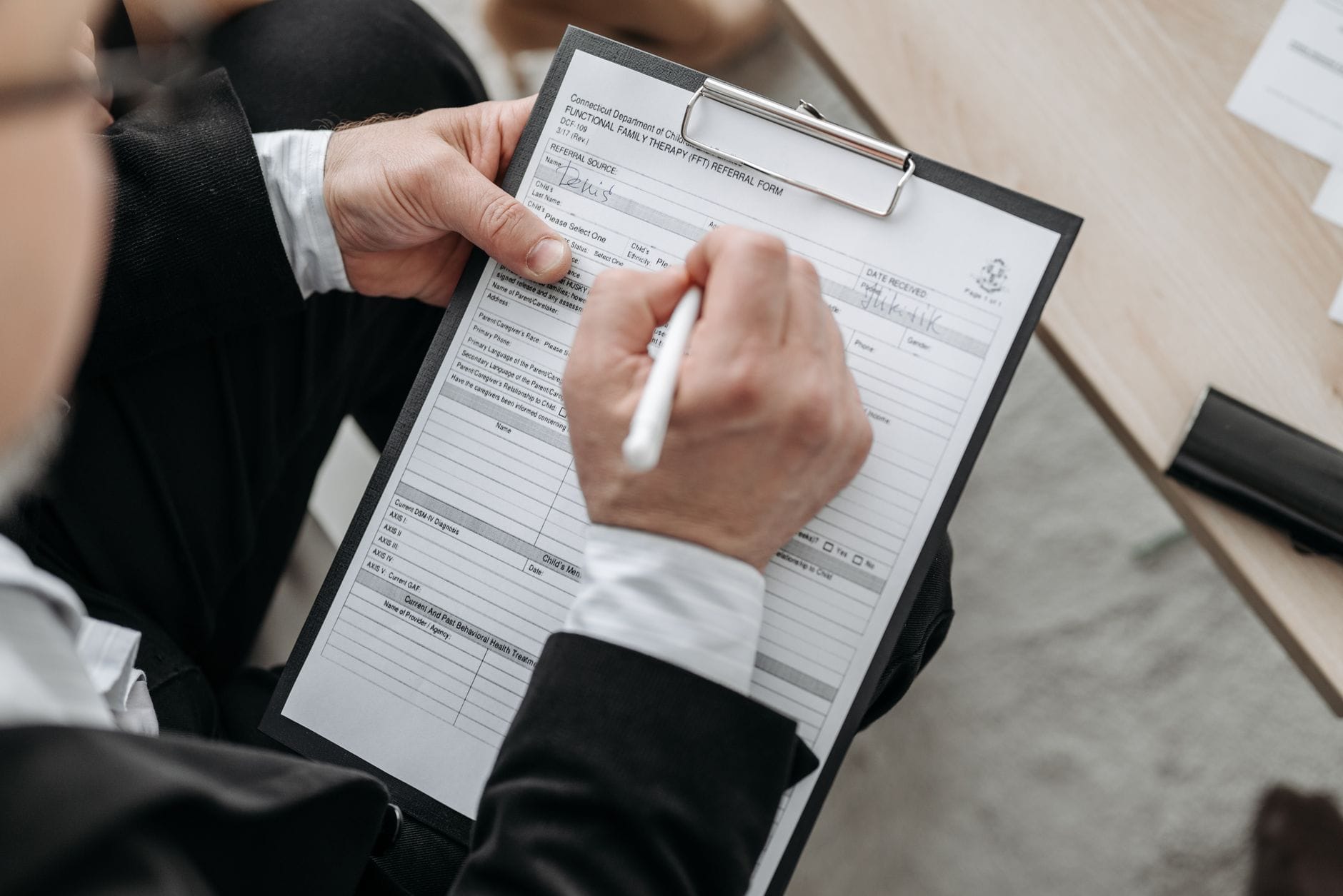 Zbliżenie na rękę mężczyzny podpisującego formalny dokument na podkładce