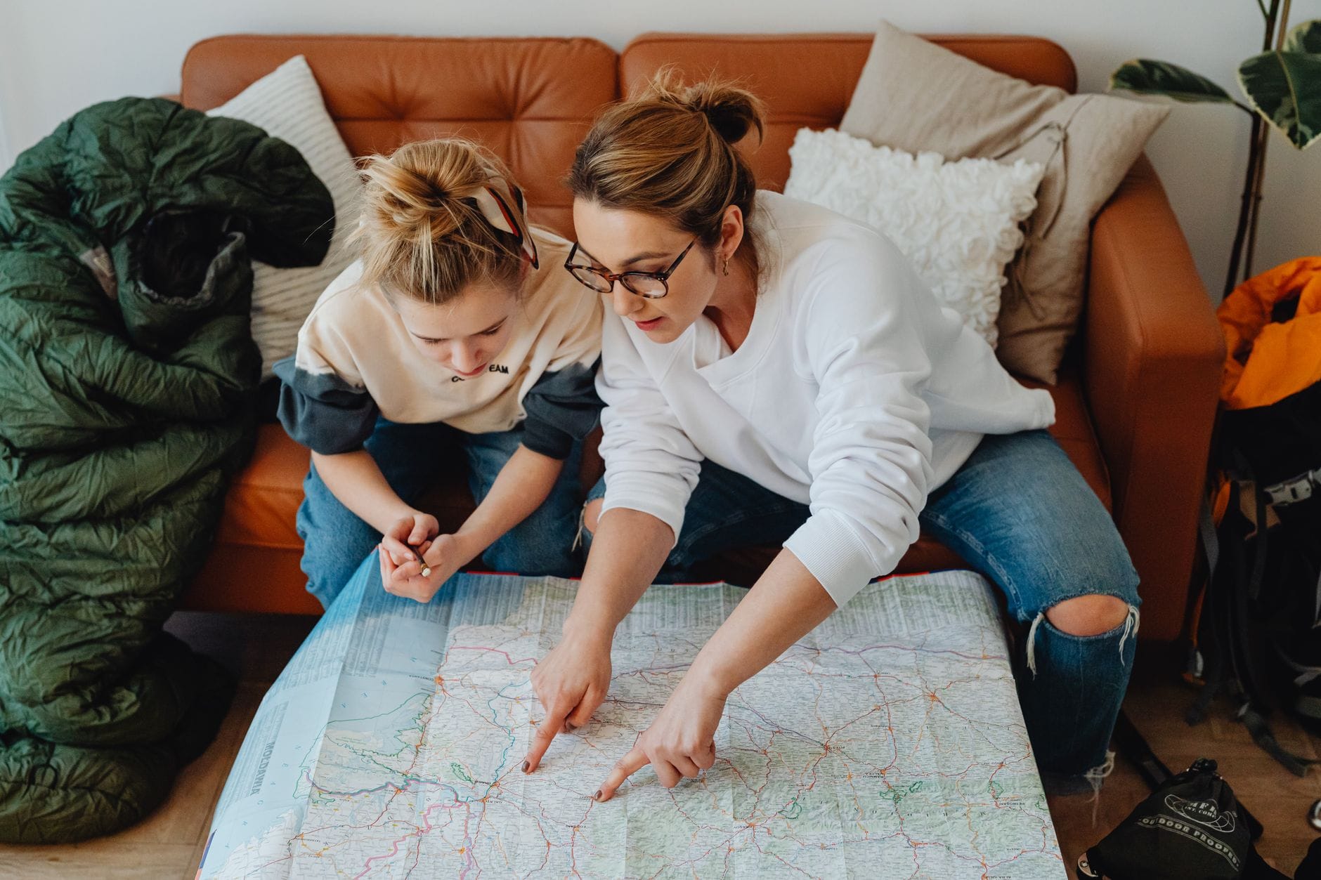 Mama z córką planują wakacje z mapą na kanapie Mama z córką planują wakacje z mapą na kanapie
