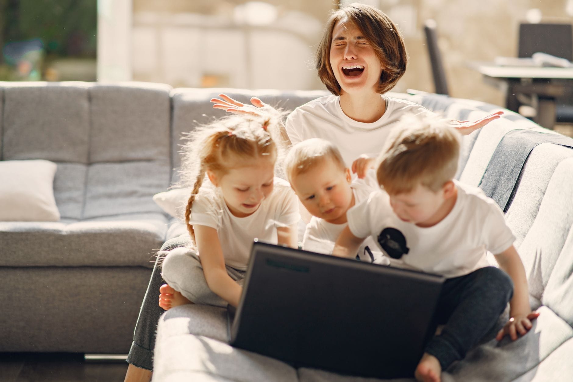 Zestresowana mama prosząca o pomoc, gdy dzieci bawią się przy laptopie Zestresowana mama prosząca o pomoc, gdy dzieci bawią się przy laptopie